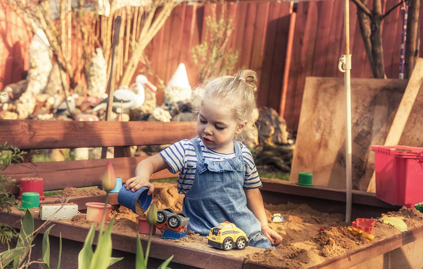 Ein Sandksten für Spiel und Spaß im Garten für die Kleinen Kleines Mädchen spielt im Sandkasten