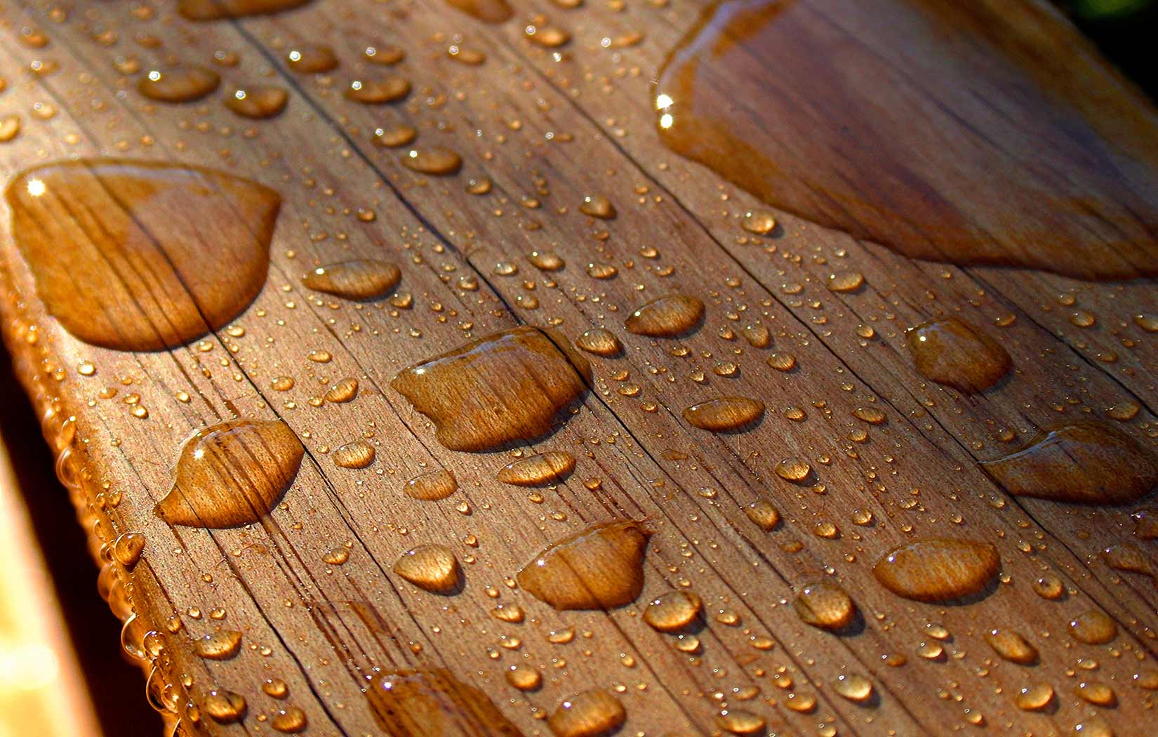 Holzschutz von Holz im Garten mit dem richtigen Anstrich Holz im Garten gestrichen mit Wassertropfen